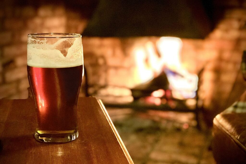 Pint of beer in front of a fire.