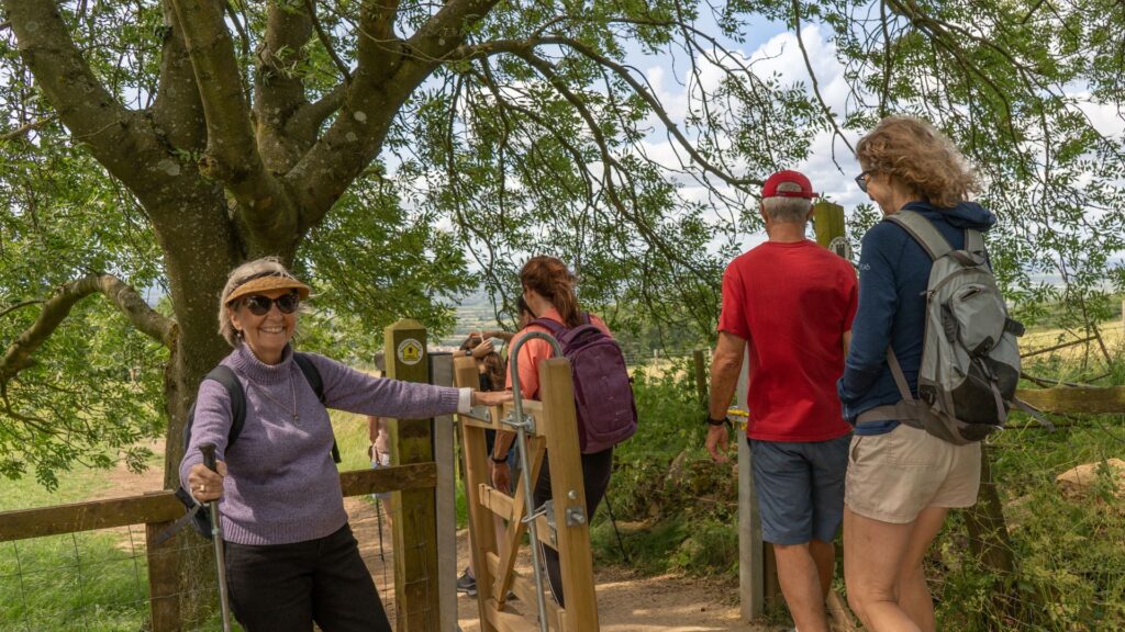 Walker holding gate open in the Cotswolds, England
