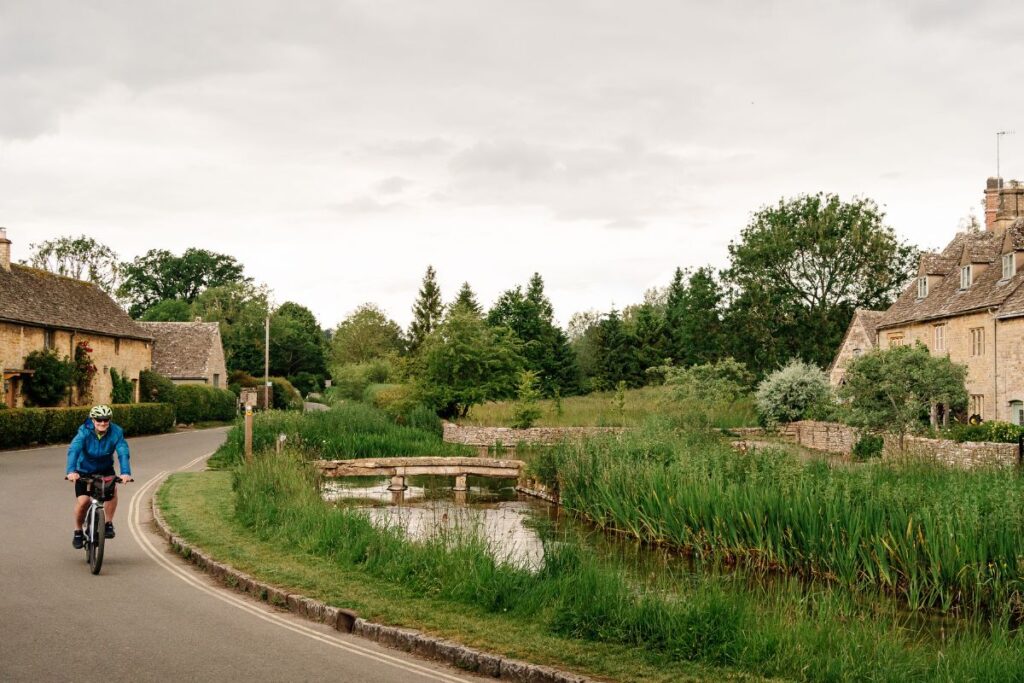 Cyclist rides through a Cotswold village